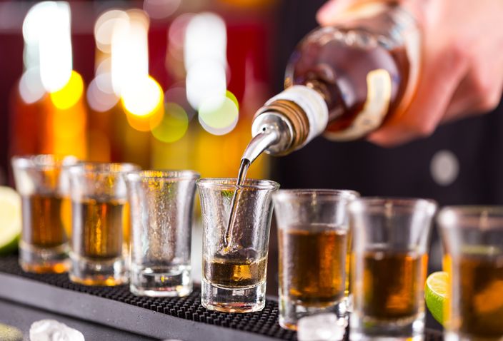 Barman pouring hard spirit into glasses