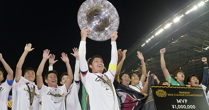 Kashima Antlers' Mitsuo Ogasawara (40) celebrates with trophies after beating Urawa Reds 2-1 in their second leg soccer match of the J-League Championship Final at Saitama Stadium in Saitama, near Tokyo, Saturday, Dec. 3, 2016. Kashima claimed their eighth title. (Yohei Kanasashi/Kyodo News via AP)