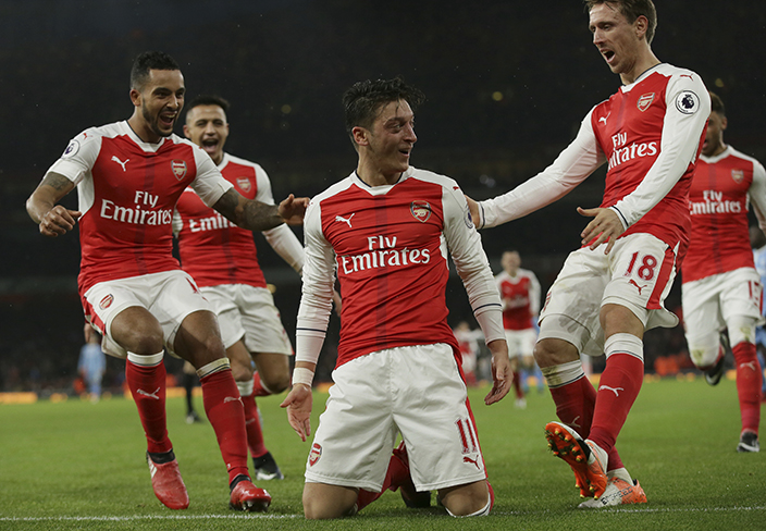 Arsenal's Mesut Ozil, centre, celebrates with his teammates after scoring a goal during the English Premier League soccer match between Arsenal and Stoke City at the Emirates stadium in London, Saturday Dec. 10, 2016. (AP Photo/Tim Ireland)