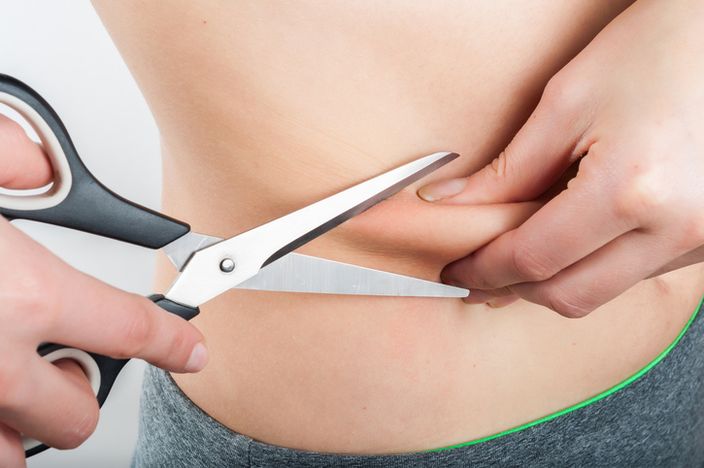 woman holding scissors to the belly on white background