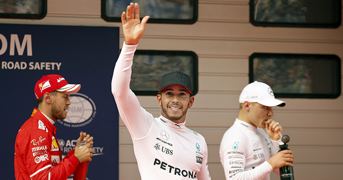 Mercedes driver Lewis Hamilton of Britain, center, waves next to his teammate Valtteri Bottas of Finland, right, and Ferrari driver Sebastian Vettel of Germany after taking pole position for the Chinese Formula One Grand Prix at the Shanghai International Circuit in Shanghai, China, Saturday, April 8, 2017. Vettel was second ahead of Bottas. (AP Photo/Andy Wong)