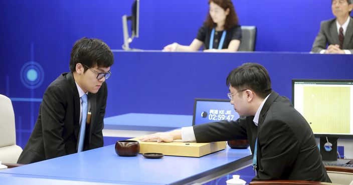 Chinese Go player Ke Jie, left, looks at the board as a person makes a move on behalf of Google's artificial intelligence program, AlphaGo, during a game of Go at the Future of Go Summit in Wuzhen in eastern China's Zhejiang Province, Tuesday, May 23, 2017. A computer that plays go has started a match against China's No. 1 player in a test of whether artificial intelligence can master one of the last games that machines have yet to dominate. (Chinatopix via AP)