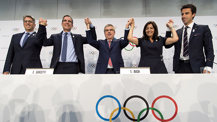 From left, Casey Wasserman, Chairman of Los Angeles 2024, Eric Garcetti, Mayor of Los Angeles, International Olympic Committee, IOC, President Thomas Bach, Anne Hidalgo, Mayor of Paris, Tony Estanguet, Co-president of Paris 2024, gesture, during a press conference after the International Olympic Committee (IOC) Extraordinary Session, at the SwissTech Convention Centre, in Lausanne, Switzerland, Tuesday, July 11, 2017. ﻿If they can agree who goes first, Paris and Los Angeles will be awarded the 2024 and 2028 Olympics. ﻿International Olympic Committee members voted unanimously to seek a consensus three-way deal between the two bid cities and the IOC executive board. Talks will open with Paris widely seen as the favorite for 2024. (Jean-Christophe Bott,Keystone via AP)