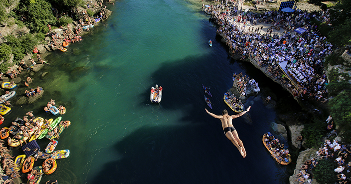 In this photograph taken on Sunday, July 30, 2017, a man dives from the Old Bridge in Mostar, Bosnia, during an annual diving competition that has been drawing crowds for more than 4.5 centuries. More than 10,000 spectators converged on the southern Bosnian city at the weekend to watch 41 daring men take a jump from the 27-meter-high historic Old Bridge into the cold, fast-flowing Neretva River below, as part of the Mostar's 451st annual diving competition.(AP Photo/Amel Emric)