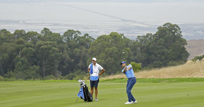 Golden State Warriors NBA basketball player Stephen Curry hits his approach shot to the 18th green during the Web.com Tour's Ellie Mae Classic golf tournament Thursday, Aug. 3, 2017, in Hayward, Calif. In the background is the San Mateo Bridge and San Francisco Bay. (AP Photo/Eric Risberg)