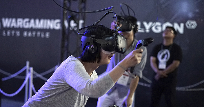 Visitors try out a game with a virtual reality headset device at the Tokyo Game Show in Chiba, near Tokyo, Thursday, Sept. 21, 2017. The Japanese video game industry is finding its way out of the doldrums, by adapting new technology for decades-old titles. And that energy was evident at the annual game show. (AP Photo/Eugene Hoshiko)