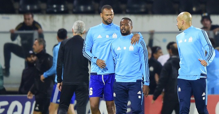 Marseille's Patrice Evra, center right, is led away by his teammate Rolando after a scuffle with Marseille supporters who trespassed into the field before the Europa League group I soccer match between Vitoria SC and Olympique de Marseille at the D. Afonso Henriques stadium in Guimaraes, Portugal, Thursday, Nov. 2, 2017. Evra was shown a red card before the start of the match for his involvement in the incident. (AP Photo/Luis Vieira)