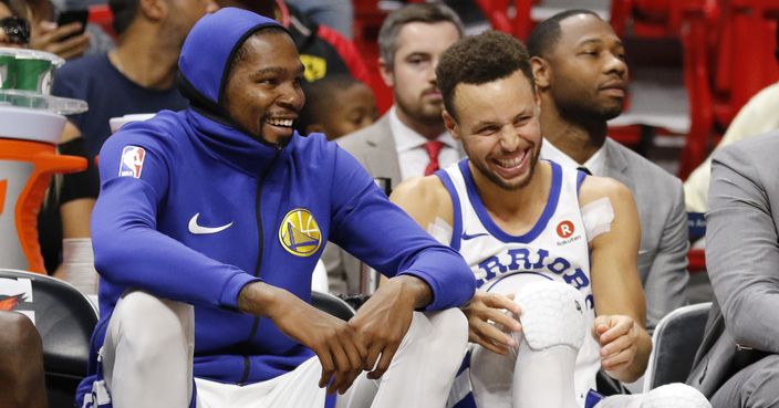 Golden State Warriors' Stephen Curry, right, and Kevin Durant react on the bench late in the fourth quarter against the Miami Heat in an NBA basketball game Sunday, Dec. 3, 2017, in Miami. The Warriors won 123-95. (AP Photo/Joe Skipper)