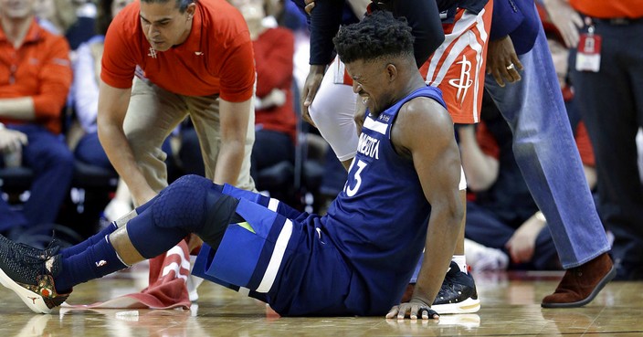 Minnesota Timberwolves guard Jimmy Butler (23) reacts to a knee injury on the court as Houston Rockets guard Chris Paul (3) and team trainers hover over him during the second half of an NBA basketball game Friday, Feb. 23, 2018, in Houston. (AP Photo/Michael Wyke)