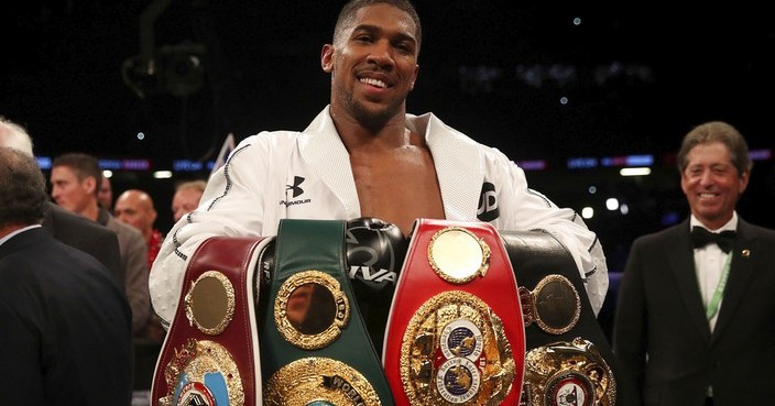 Anthony Joshua celebrates with his belts after victory over Joseph Parker to become the WBA, IBF and WBO heavyweight champion at the Principality Stadium in Cardiff, Wales, Saturday March 31, 2018.  (Nick Potts/PA via AP)