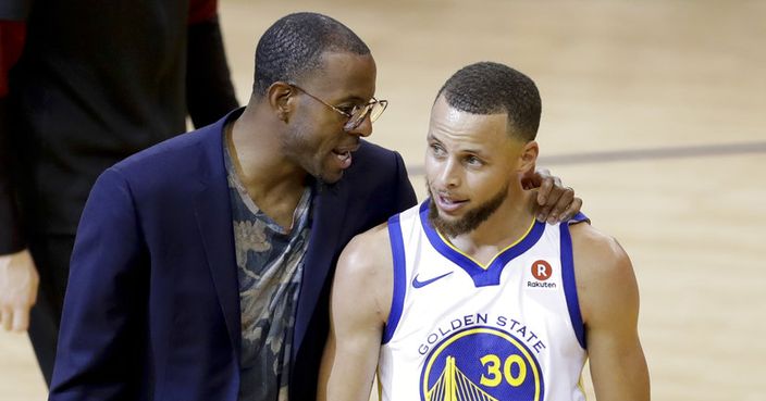 Golden State Warriors guard Stephen Curry (30) walks with injured forward Andre Iguodala, in suit, after scoring against the Cleveland Cavaliers during the first half of Game 1 of basketball's NBA Finals in Oakland, Calif., Thursday, May 31, 2018. (AP Photo/Marcio Jose Sanchez)