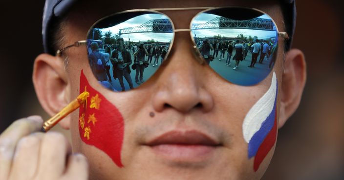 A fan gets a Chinese flag painted onto his face prior to the opening match between Russia and Saudi Arabia during the 2018 soccer World Cup at the Luzhniki stadium in Moscow, Russia, Thursday, June 14, 2018. (AP Photo/Rebecca Blackwell)