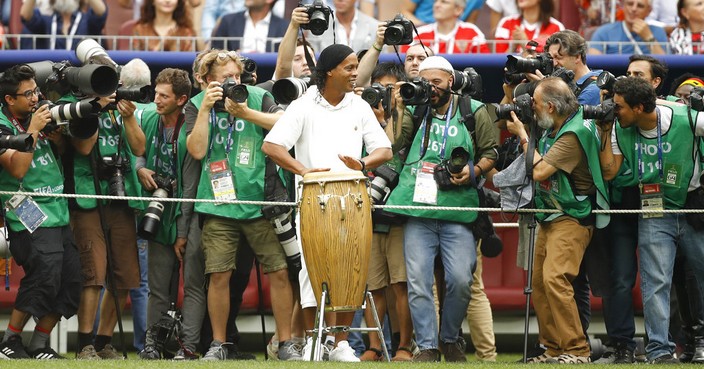 Former Brazilian soccer player Ronaldinho, centre, surrounded by photographers plays on the drums as he takes part in the closing ceremony before the start of the the final match between France and Croatia at the 2018 soccer World Cup in the Luzhniki Stadium in Moscow, Russia, Sunday, July 15, 2018. (AP Photo/Francisco Seco)