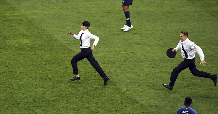 France's Raphael Varane, top, and France's Samuel Umtiti look at two people that invaded the pitch during the final match between France and Croatia at the 2018 soccer World Cup in the Luzhniki Stadium in Moscow, Russia, Sunday, July 15, 2018. (AP Photo/Thanassis Stavrakis)