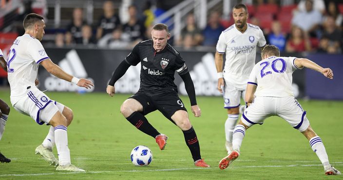 D.C. United forward Wayne Rooney (9) dribbles the ball against Orlando City midfielder Oriol Rosell (20) and defender Shane O'Neill, left, during the first half of an MLS soccer match, Sunday, Aug. 12, 2018, in Washington. (AP Photo/Nick Wass)