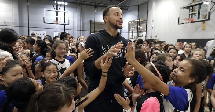 Golden State Warriors' Stephen Curry, center, greets basketball camp participants after taking a group photo at Ultimate Fieldhouse in Walnut Creek, Calif., Tuesday, Aug. 14, 2018. For the first time, Curry hosted only girls for a free, Warriors-run camp Monday and Tuesday at Walnut Creek's Ultimate Fieldhouse. Last week at the same facility that he has also chosen in recent years, the Golden State star held his Under Armour 