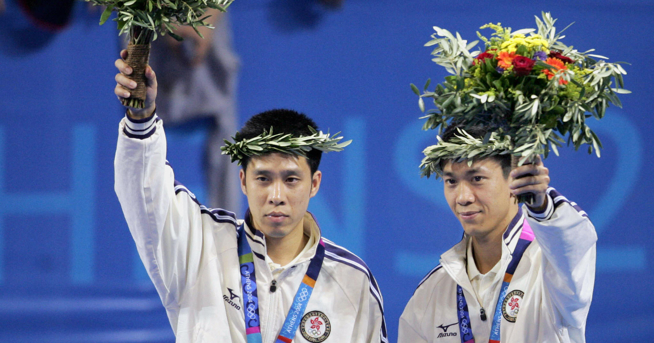 Athens, GREECE:  Hong Kong's Ko Lai Chak (L) and Li Ching wave on the podium after being awarded the silver medal in the men's doubles table tennis final at the Olympic Games in Athens, 21 August 2004.  China's Ma Lin and Chen Qi beat Ko Lai Chak and Li Ching 11-6, 11-9, 7-11, 11-8, 8-11, 11-5 to take gold.  AFP PHOTO / RAMZI HAIDAR  (Photo credit should read RAMZI HAIDAR/AFP/Getty Images)