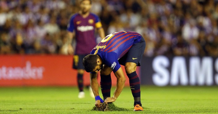 FC Barcelona's Luis Suarez, foreground fixes the grass during the Spanish La Liga soccer match between FC Barcelona and Valladolid at the Nuevo Jose Zorrilla stadium in Valladolid, Spain, Saturday, Aug. 25, 2018. (AP Photo/Andrea Comas)