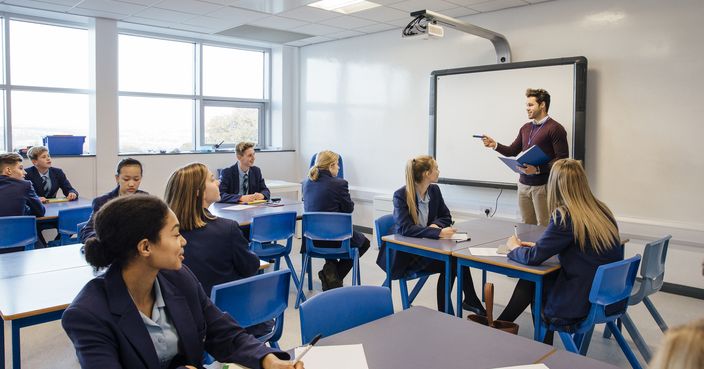 Male teacher is teaching a group of teenagers in a high school lesson.