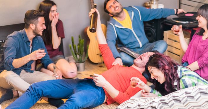 Happy friends having fun in hostel living room drinking and laughing  - Young students enjoying time together listening music with vinyl records - Main focus on cente woman face - Party concept