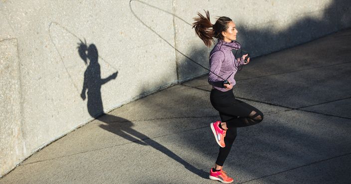 Fitness woman skipping with a jump rope outdoors. Female doing fitness training in morning.