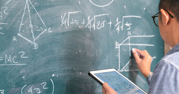 The science professor writes on the board while having a blackboard and a blackboard.