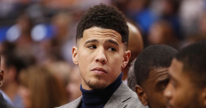 Phoenix Suns guard Devin Booker looks on from the bench during the first half of an NBA basketball game against the Dallas Mavericks, Wednesday, Jan. 9, 2019, in Dallas. Booker did not play due to an earlier injury. (AP Photo/Jim Cowsert)