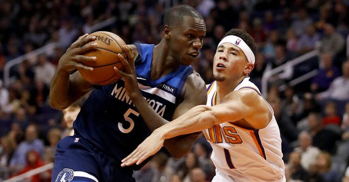 Minnesota Timberwolves center Gorgui Dieng (5) takes the ball away from Phoenix Suns guard Devin Booker (1) during the second half of an NBA basketball game, Tuesday, Jan. 22, 2019, in Phoenix. The Timberwolves won 118-91. (AP Photo/Matt York)