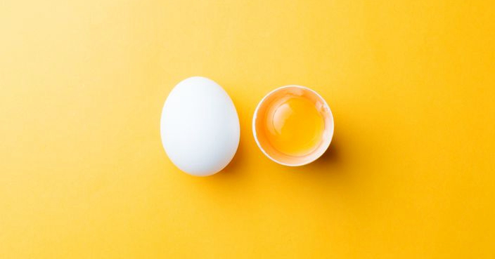 White egg and egg yolk on the yellow background.