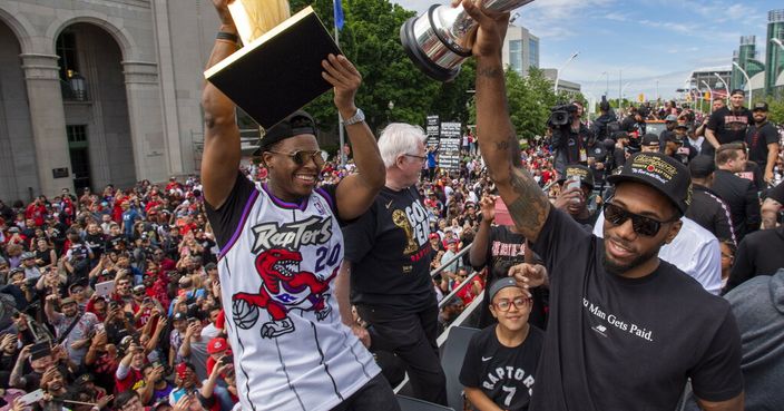 Toronto Raptors' Kawhi Leonard and Kyle Lowry hold up trophies as they celebrate during the team's NBA basketball championship parade in Toronto, Monday, June 17, 2019. (Frank Gunn/The Canadian Press via AP)
