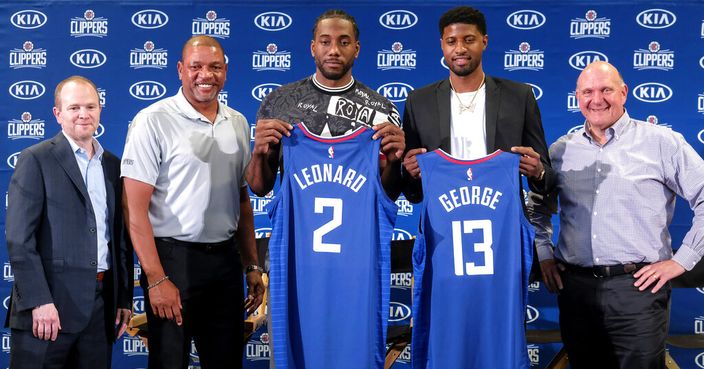 Kawhi Leonard, center, and Paul George , second right, holding their new team jerseys, pose with Los Angeles Clippers President of Basketball Operations Lawrence Frank, left, head coach Doc Rivers, second left, and team chairman Steve Ballmer during a press conference in Los Angeles, Wednesday, July 24, 2019. Nearly three weeks after the native Southern California superstars shook up the NBA by teaming up with the Los Angeles Clippers, the dynamic duo makes its first public appearance. (AP Photo/Ringo H.W. Chiu)