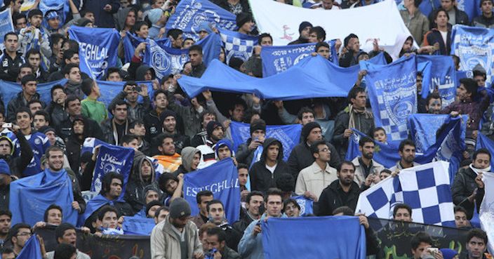 FILE  - In this Dec. 9, 2011 file photo, supporters of Iranian soccer team Esteghlal, hold flags of their favorite team, at the Azadi (Freedom) stadium, in Tehran, Iran. Sahar Khodayari, an Iranian female soccer fan died after setting herself on fire outside a court after learning she may have to serve a six-month sentence for trying to enter a soccer stadium where women are banned, a semi-official news agency reported Tuesday, Sept. 10, 2019. The 30-year-old was known as the 