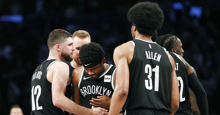 Brooklyn Nets guard Joe Harris (12) and center Jarrett Allen (31) console guard Kyrie Irving, center, after Irving collapsed on the floor after missing a shot at the end of overtime in the team's NBA basketball game against the Minnesota Timberwolves, Wednesday, Oct. 23, 2019, in New York. The Timberwolves won 127-126. Irving scored 50 points. (AP Photo/Kathy Willens)