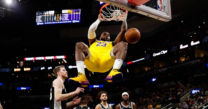Los Angeles Lakers forward LeBron James (23) hangs on the rim as he scores against the San Antonio Spurs during the first half of an NBA basketball game, in San Antonio, Monday, Nov. 25, 2019. (AP Photo/Eric Gay)