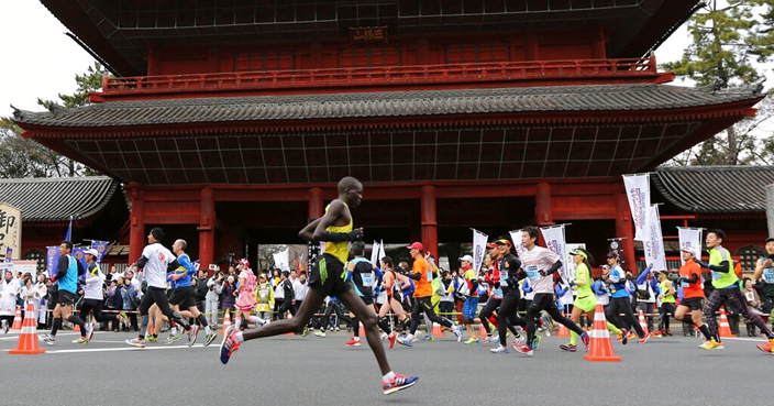 FILE - In this Feb. 23, 2014, file photo, runners pass by Zojoji Buddhist temple during the Tokyo Marathon in Tokyo. Tokyo Metropolitan Government was considering making a proposal, the start times at 3 a.m. or 5 a.m., hoping to keep the 2020 Tokyo Olympic marathon in Tokyo, Japanese news agency Kyodo News said on Thursday, Oct. 24, 2019. That could be proposed to Olympic organizers and the IOC, a move to keep the marathon from being moved out of Tokyo’s summer heat to cooler summer weather 800 kilometers (500 miles) further north in Sapporo. (AP Photo/Eugene Hoshiko, File)