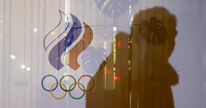 FILE - In this Nov. 18, 2015 file photo a man walking past the Russian Olympic Committee building, casts a shadow on a window in Moscow, Russia. The World Anti-Doping Agency banned Russia on Monday Dec. 9, 2019 from the Olympics and other major sporting events for four years, though many athletes will likely be allowed to compete as neutral athletes. (AP Photo/Pavel Golovkin, file)