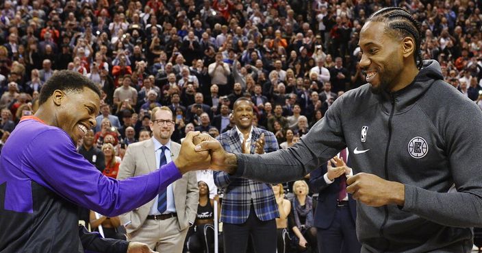 Former Toronto Raptors and now Los Angeles Clippers forward Kawhi Leonard, right, receives his 2019 NBA championship ring from Raptors' Kyle Lowry prior to an NBA basketball game, Wednesday, Dec. 11, 2019, in Toronto. (Nathan Denette/The Canadian Press via AP)