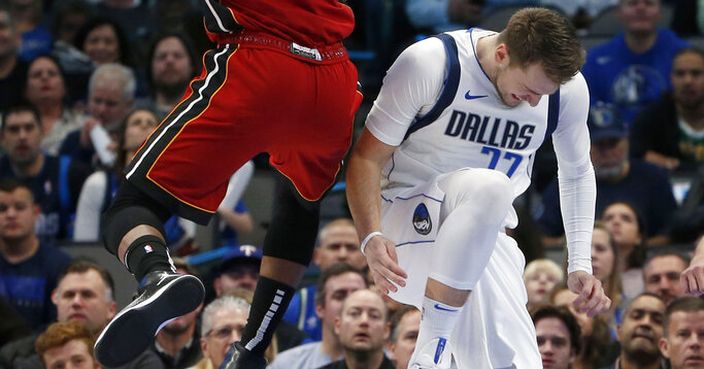 Dallas Mavericks forward Luka Doncic (77) reacts after injuring himself as Miami Heat forward Jimmy Butler (22) defends him during the first half of an NBA basketball game in Dallas, Saturday, Dec 14, 2019. (AP Photo/Michael Ainsworth)