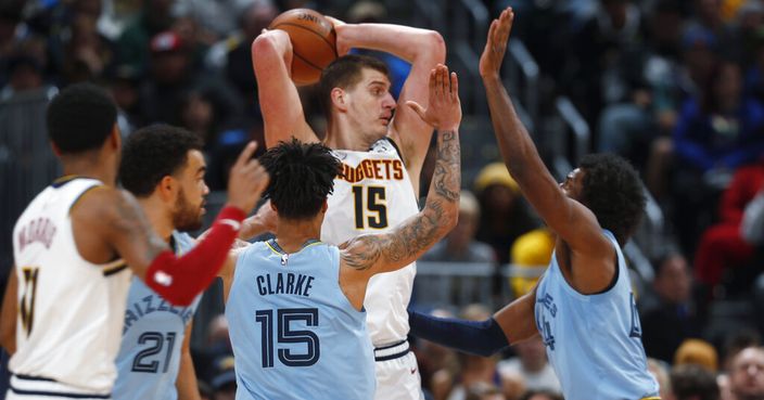 Denver Nuggets center Nikola Jokic, center top, looks to pass the ball while trapped in the corner by Memphis Grizzlies guard Tyus Jones (21) and forwards Brandon Clarke, center front, and Solomon Hill, right, in the second half of an NBA basketball game Saturday, Dec. 28, 2019, in Denver. (AP Photo/David Zalubowski)
