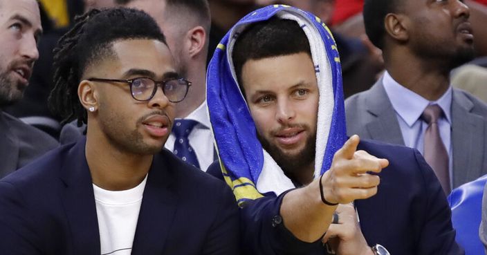 Golden State Warriors' Stephen Curry, right, gestures while speaking to teammate D'Angelo Russell on the bench as they watch during the second half of the team's NBA basketball game against the Milwaukee Bucks on Wednesday, Jan. 8, 2020, in San Francisco. (AP Photo/Ben Margot)