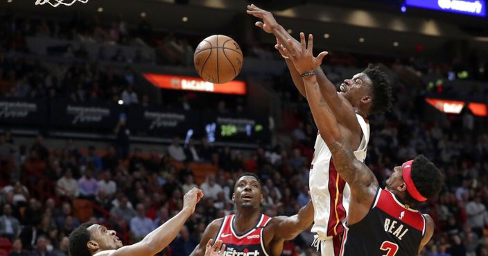 Miami Heat forward Jimmy Butler, second from right, is fouled by Washington Wizards guard Bradley Beal (3) during overtime in an NBA basketball game, Wednesday, Jan. 22, 2020, in Miami. The Heat won 134-129 in overtime. (AP Photo/Lynne Sladky)