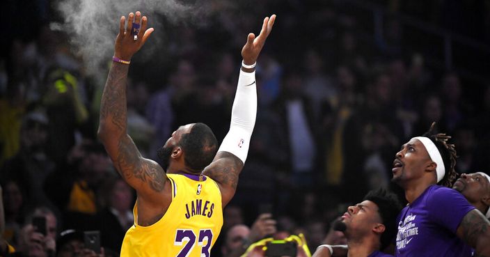 Los Angeles Lakers forward LeBron James, left, tosses powder in the air as teammates watch prior to an NBA basketball game against the Phoenix Suns Monday, Feb. 10, 2020, in Los Angeles. (AP Photo/Mark J. Terrill)
