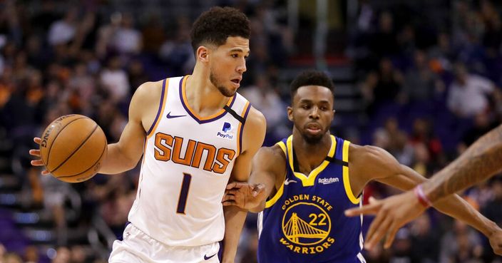 Phoenix Suns guard Devin Booker (1) looks to pass as Golden State Warriors guard Andrew Wiggins (22) defends during the second half of an NBA basketball game, Wednesday, Feb. 12, 2020, in Phoenix. (AP Photo/Matt York)