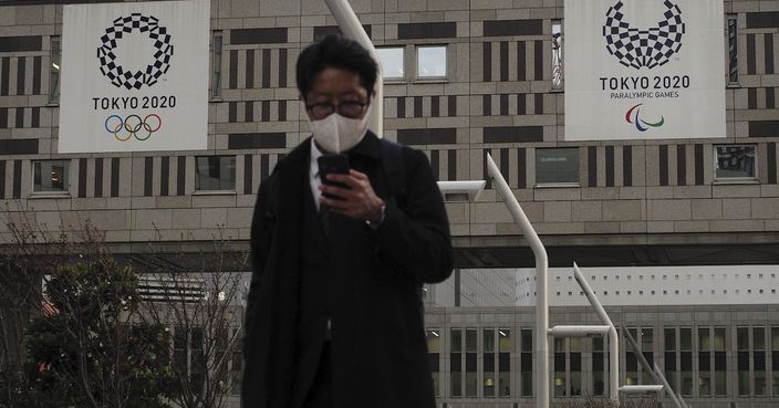 A man with a mask walks past the Tokyo Metropolitan Government building adorned with banners promoting the Tokyo 2020 Olympics Friday, March 27, 2020, in Tokyo. Japan seemed to have the virus infection contained, until it finally relinquished the Olympics. Now, Tokyoﾕs cases spiking, it governor is requesting stay-at-home requests and hinting a possible lockdown down the road. (AP Photo/Jae C. Hong)