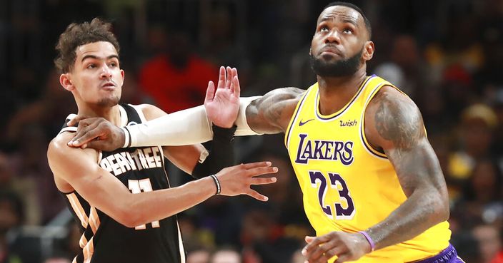 Los Angeles Lakers forward LeBron James, right, pushes Atlanta Hawks guard Trae Young out of the way as he prepares to grab a jump ball during the second half of an NBA basketball game Sunday, Dec. 15, 2019, in Atlanta. (Curtis Compton/Atlanta Journal-Constitution via AP)